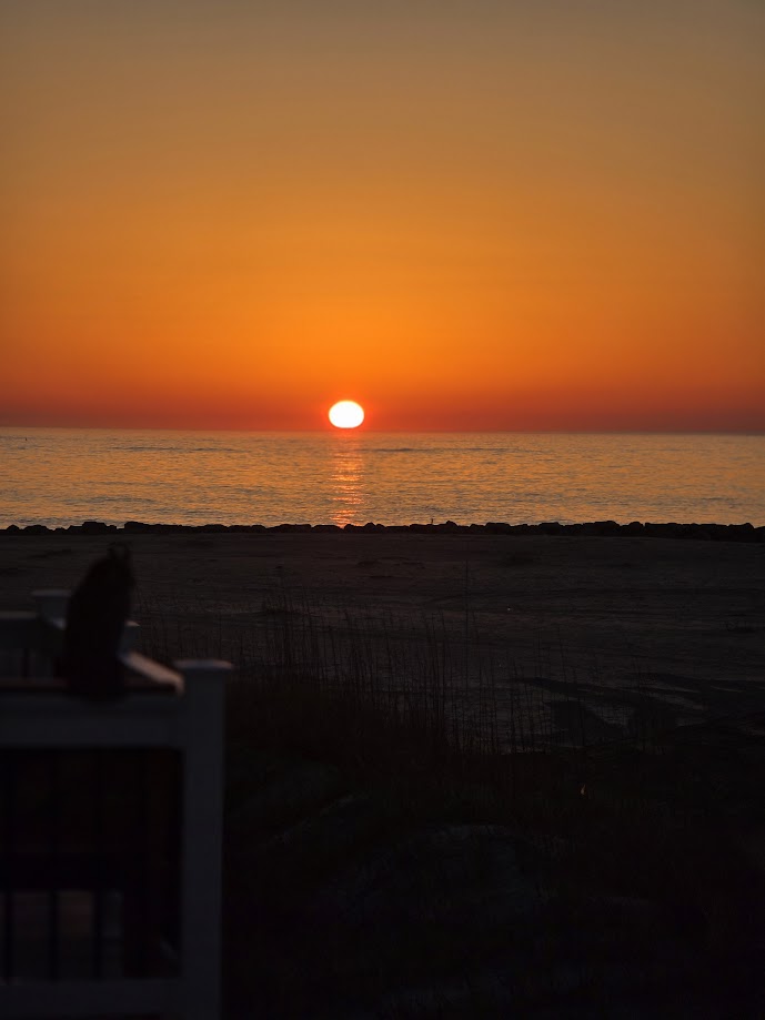 Sunset over calm ocean waves with a vibrant orange sky