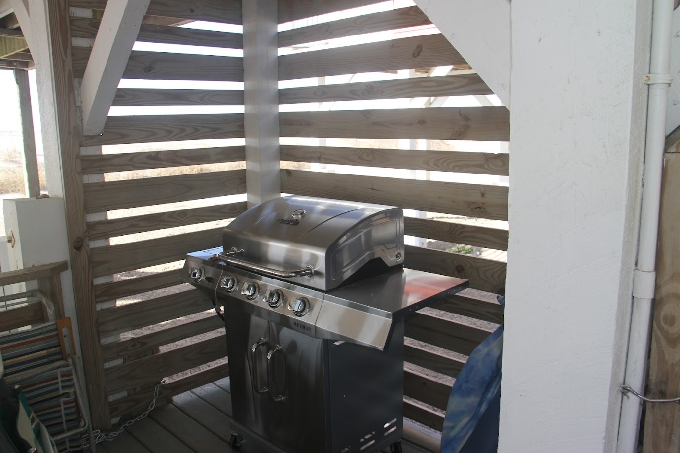 Stainless steel gas grill with multiple burners in a wooden slatted corner