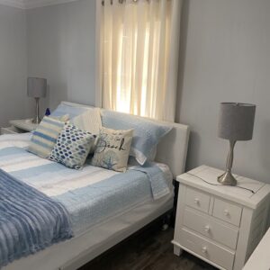 A cozy bedroom features a bed with blue and white striped linens