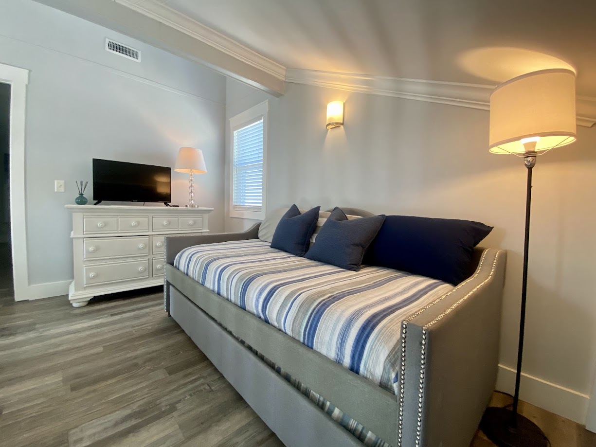 A cozy bedroom with a striped daybed, blue and gray pillows