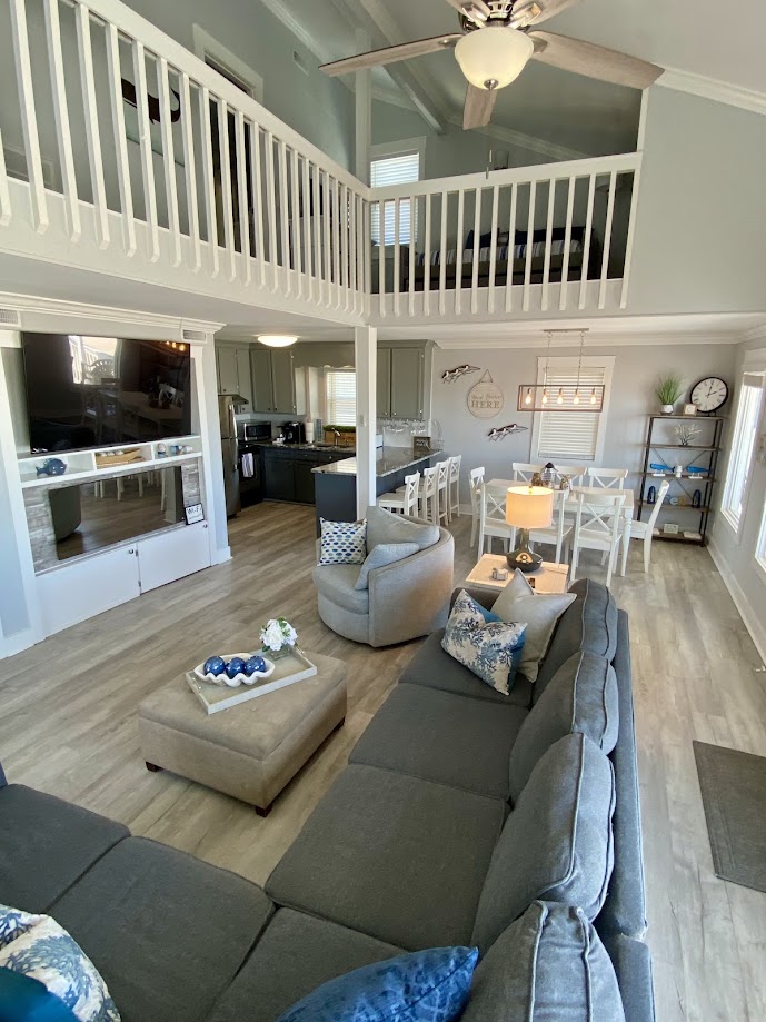 Spacious living area with a gray sectional, patterned pillows, ceiling fan